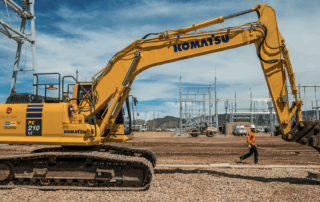 Yellow Komatsu excavator operated by Grade Tech on a construction site under clear blue skies, symbolizing growth and innovation in the construction industry.